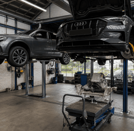 Audi auto reparatie en onderhoud in werkplaats met twee auto's op hefbruggen.