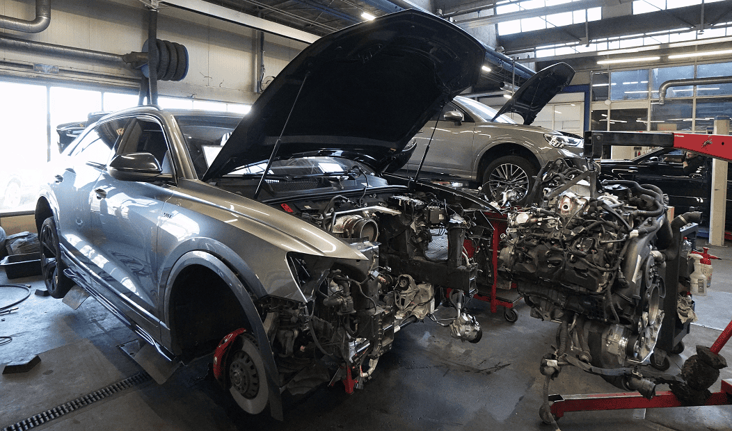 Audi Q5 in reparatie, motor en onderdelen verwijderd in werkplaats.