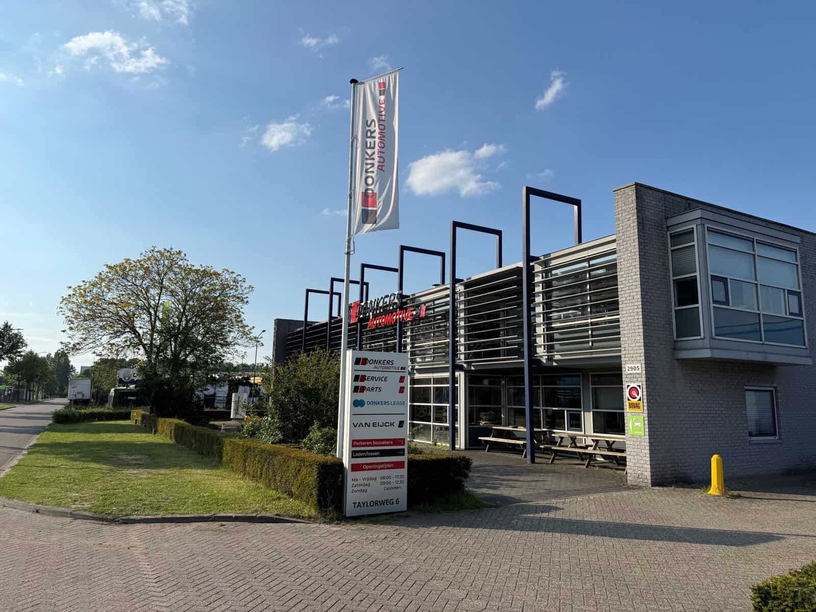 Modern autodealergebouw van Donkers VAG met vlaggen en gevelreclame.